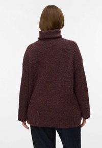 Pull à col roulé bordeaux avec une coupe ample, tricot texturé et épaules tombantes. Doté d'un ourlet côtelé et d'un design mi-long.