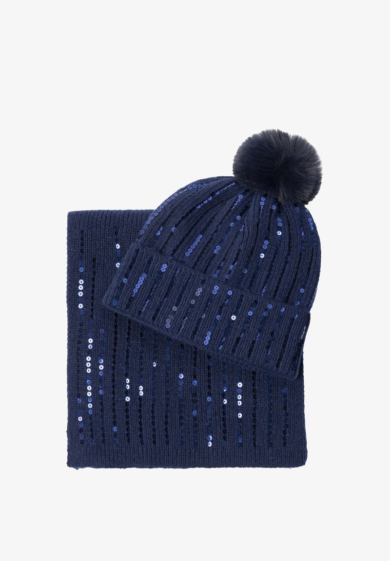 Bonnet en tricot bleu marine avec pompon et écharpe assortie, tous deux ornés de rangées verticales de paillettes bleues.