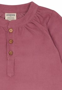 Geribbelde, biologische katoenen top in gedempt mauve, met een ronde halslijn, een knoopsluiting met drie houten knopen en geplooide details.