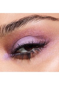 Close-up van een paarse oogschaduwlook met glinsterende texturen, featuring een geblend verloop van lichte en donkere paarstinten op het ooglid.