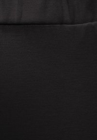 Black, textured fabric with a fine knit pattern; two sections joined at a horizontal seam, creating a smooth and consistent surface.