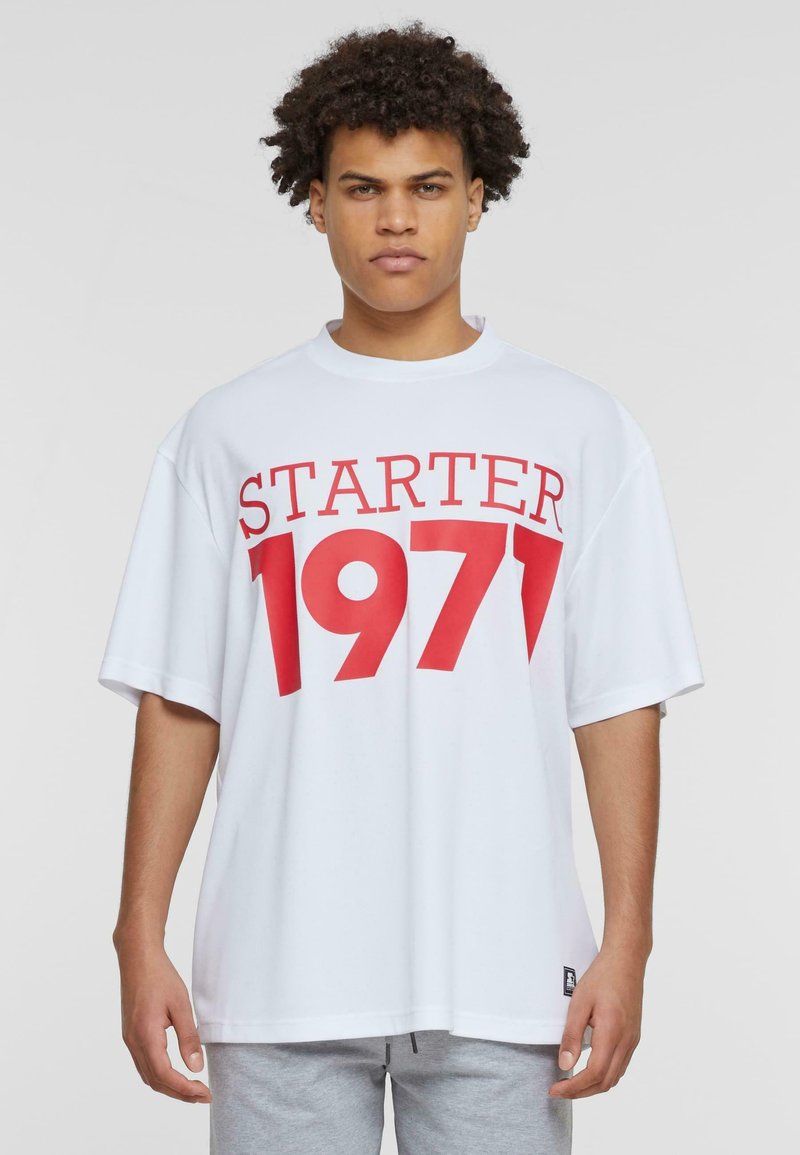 Balta trumpa rankovėmis marškinėliai su dideliu raudonu "STARTER 1971" spaudiniu ant priekio, pagaminti iš glotnaus, kvėpuojančio audinio.