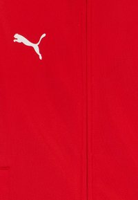 Rdeč poliester tkanina z belim logotipom Puma. Gladka tekstura brez vidnih vzorcev in enobarven dizajn.