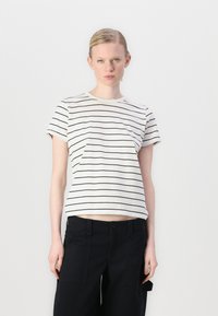 T-shirt a righe in crema chiaro con sottili righe orizzontali nere, maniche corte e una vestibilità rilassata, abbinata a pantaloni cargo neri.