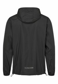 Svart lättviktig jacka med huva, elastiska ärmslut och dragsko i sidorna. Har texten "U.S. POLO ASSN." på den nedre delen av ryggen.