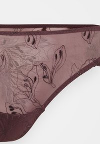 String en dentelle bordeaux avec broderies florales, tissu semi-transparent et une délicate finition le long de la taille et des ouvertures de jambes.