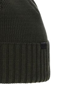 Cappello beanie lavorato a maglia di colore verde scuro. Texture a coste con un superiore liscio, dotato di un piccolo tag in pelle nera sul lato.