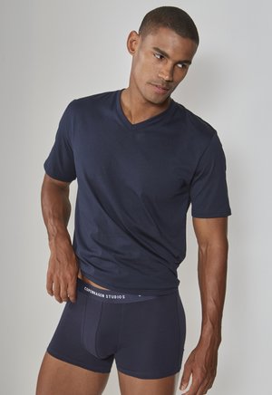 Navy blue V-neck t-shirt made of soft fabric, paired with dark blue boxer briefs featuring a white logo waistband. Close-up fit.