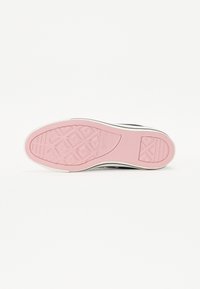 Sola de ténis em preto e branco com uma sola de borracha rosa, apresentando um padrão texturizado e detalhe do logótipo. Bordas delineadas a branco.