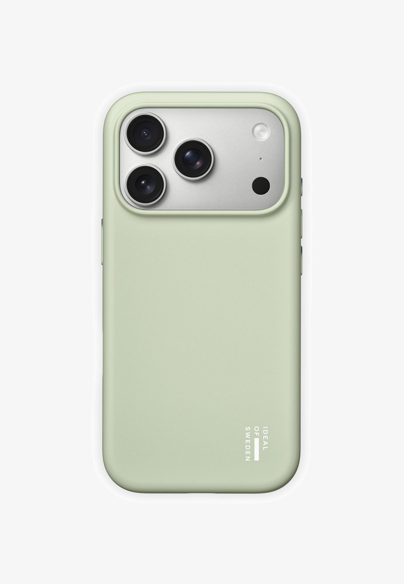 Coque de téléphone vert clair étiquetée "Ideal of Sweden" protégeant un smartphone avec trois caméras arrière et un flash sur un panneau argenté.