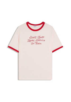 Biała koszulka z czerwoną lamówką na rękawach i kołnierzu, z czerwonym napisem „Don't Cross Lines, Dance On Them” w zabawnym kroju pisma.