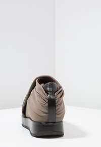 Scarpa in tessuto marrone con design arricciato sul retro, accentuata da un inserto in pelle nera texturizzata e una suola in gomma spessa.