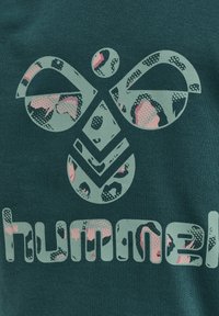 Donkergroene sweatshirt met een groot logo in lichtgroen en roze luipaardprintaccenten, textuurstof en vetgedrukte typografie.