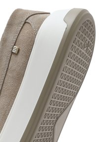 Beige suede sneaker with a white rubber sole. Features a textured outsole for grip and a subtle logo accent on the side.