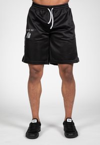 Zwarte sportshorts van lichtgewicht, ademend materiaal met een tailleband met trekkoord. Kenmerkt zich door witte accenten en branding aan de zijkant.