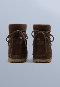 Brązowe zamszowe botki za kostkę z okrągłym noskiem, teksturowaną powierzchnią i sznurowadłami z tyłu. Gumowe podeszwy z wzorami zapewniającymi przyczepność.