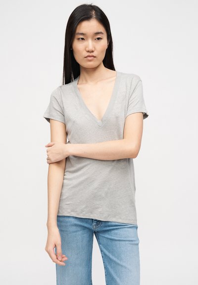 Γκρι κοντομάνικο μπλουζάκι V-λαιμό σε άνετη γραμμή, κατασκευασμένο από μαλακό ύφασμα, με απλό σχέδιο, συνδυασμένο με ανοιχτόχρωμο μπλε τζιν.