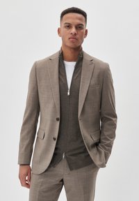 Jasnobrązowa marynarka o dopasowanym kroju z szpiczastymi klapami, slim fit, z teksturowanej tkaniny, w zestawieniu z ciemnoszarym zapinanym na zamek pod spodem.