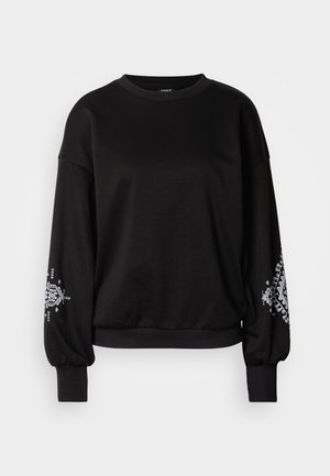 Zwarte trui met lange, opgeblazen mouwen en geribde boorden. Heeft een wit decoratief patroon op de mouwen. Soepele, zachte stof. Ronde halslijn.