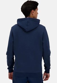 Felpa blu navy con cappuccio regolabile, polsini a coste e una texture liscia. Presenta un design semplice senza loghi o motivi visibili.