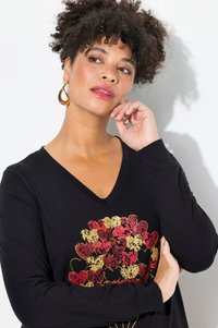Schwarz langärmliges V-Ausschnitt-Shirt mit einem goldenen und roten Herzgrafikdesign auf der Vorderseite. Hat eine weiche Textur und eine lässige Passform.