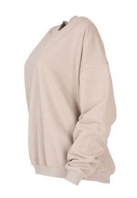 Beżowy sweter z miękkiego materiału, z okrągłym dekoltem, opuszczonymi ramionami oraz ribbowymi mankietami i dolną krawędzią. Klasyczny krój z półgolfem.