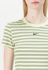 Zielona i biała w paski koszulka T-shirt z okrągłym dekoltem i krótkimi rękawami. Posiada czarne logo Nike na piersi. Wykonana z miękkiego materiału bawełnianego.