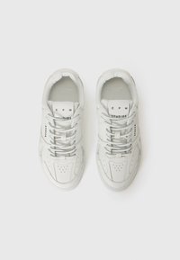 Baskets en cuir blanc avec un bout perforé, des lacets plats et un logo sur la languette. Forme arrondie avec une semelle texturée.