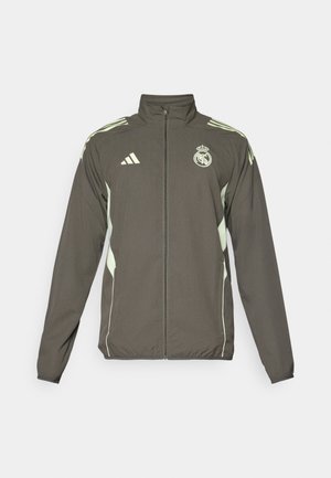 Grå jakke med høj krave, fuld lynlås og lysegrønne detaljer. Inkluderer Adidas-logoet og et våbenskjold design på brystet.