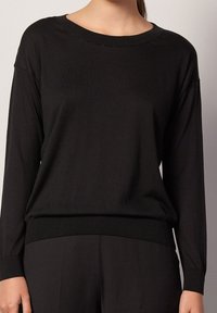 Pull noir à manches longues avec un large col rond, texture douce, coupe ample, et ourlet et poignets côtelés, fabriqué en matériau léger.