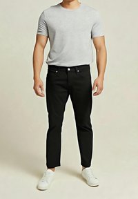 Camiseta gris de manga corta, jeans ajustados negros y zapatillas blancas. La camiseta es de algodón, los jeans tienen bolsillos delanteros y botón metálico.