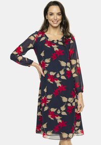 Granatowa sukienka z długimi, przezroczystymi rękawami. Posiada kwiatowy wzór w kolorze czerwonym i beżowym. Miękki, zwiewny materiał z okrągłym dekoltem i luźnym krojem.
