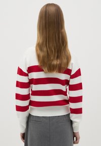 Rot-weißer gestreifter Pullover mit gerippten Bündchen und Saum. Weicher Strickstoff, verkürztes Design, sichtbare Rückendetails und strukturierter Muster.