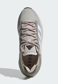 Zapatillas deportivas ligeras de malla gris con rayas blancas, que presentan cordones rosas, una parte superior de tejido texturizado y un cuello acolchado.