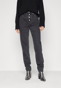 Černé denimové džíny s vysokým pasem, zapínáním na pět knoflíků, rovné nohavice a minimálním zdobením, v kombinaci s podpatkovými kotníkovými botami se špičatou špičkou.