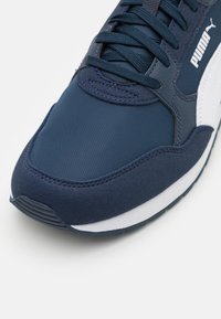 Baskets bleu marine avec une tige en textile lisse, accents blancs, semelle extérieure en caoutchouc texturé et un design à lacets avec des coutures renforcées.