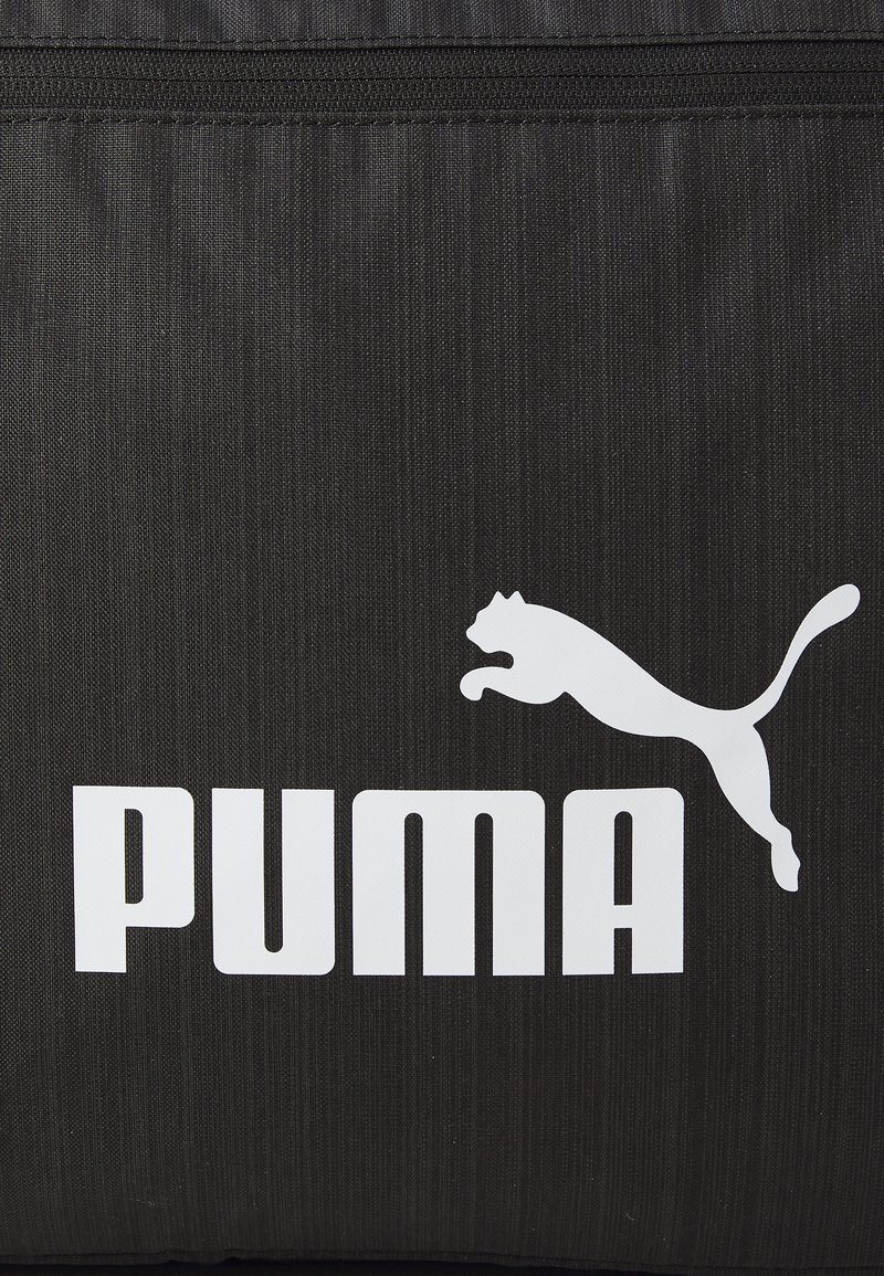 Bolsa de tela negra con un destacado logo blanco de "PUMA" y la silueta de un puma saltando. Presenta una textura suave y detalles de cremallera.