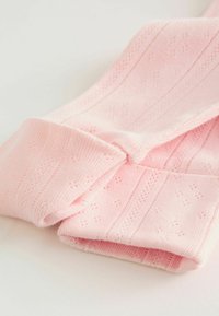 Collants tricotés roses avec un motif côtelé et de petits détails ajourés décoratifs. Texture lisse et finition douce, pliés soigneusement.