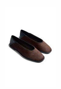 Scarpe basse marroni con tomaia testurizzata in materiale simile ai peli e tacco in pelle nera liscia, punta arrotondata e suola flessibile.