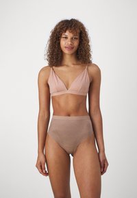 Soft, light pink bra with a v-neck design and thin straps paired with high-waisted, beige underwear featuring a smooth texture and subtle pattern.
