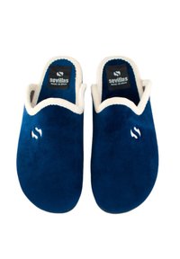 Zapatillas de ante azul marino con forro color crema y logo. Diseño abierto, textura suave y parte trasera cerrada para facilitar su uso.