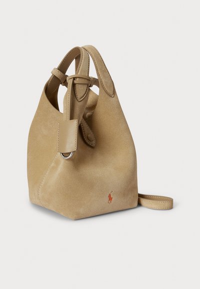 Καφέ τσαντάκι τύπου bucket από σουέντ με δερμάτινο ιμάντα και δύο κορυφαίες λαβές. Διαθέτει οβάλ άνοιγμα, ασημένια μεταλλικά στοιχεία και μικρό κεντητό λογότυπο.