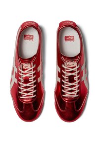 Czerwone metaliczne sneakersy z białymi akcentami, z sznurowanym zapięciem, okrągłym noskiem i teksturowaną wkładką. Logo marki na języku.