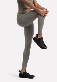 Grå sömlösa leggings med en åtsittande design, hög midja och en mjuk yta, tillsammans med svarta träningsskor med texturerade sulor.