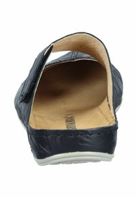 Black slip-on shoe with a rounded back, leather upper, beige insole, and textured stitching along the edges. Flat, white rubber sole.