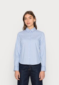 Camicia azzurra chiara con righe bianche verticali, maniche lunghe, colletto appuntito e orlo arrotondato. Vestibilità casual, tessuto morbido.