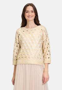 Goldfarbener gestrickter Pullover mit lockerer Passform, der offene Webmuster, Dreiviertelärmel und einen gerippten Saum aufweist. Glatte Textur.