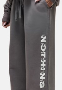 Grijze sweatpants van zachte stof, met een losse pasvorm, zijzakken en witte opdruk met sterren langs het linkerbeen.