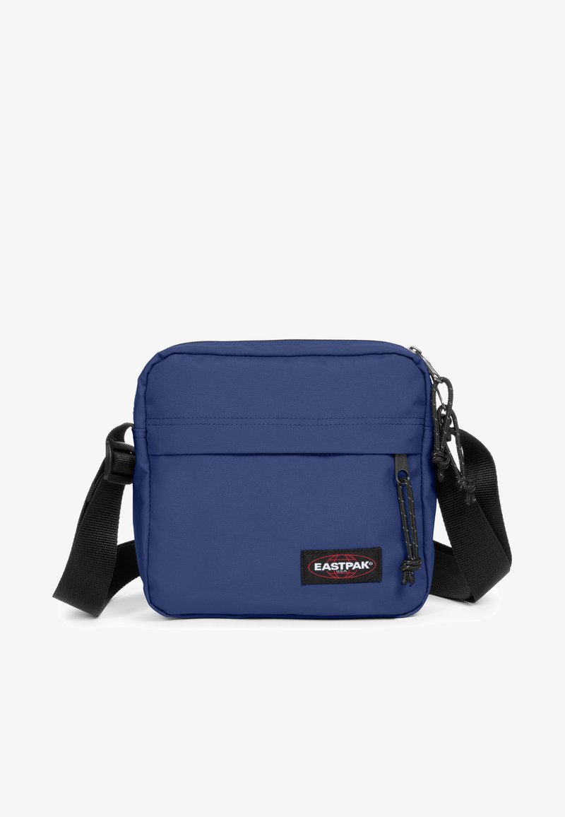 Kvadratisk blå tygaxelväska med dragkedjestängning, justerbar rem, framficka och en framträdande Eastpak-logotyp på framsidan.