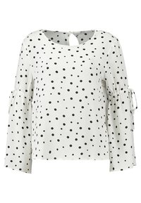 Maglietta bianca a maniche lunghe con pois neri. Presenta una scollatura a keyhole sul retro e dettagli con fiocchi sulle maniche. Realizzata in tessuto leggero.